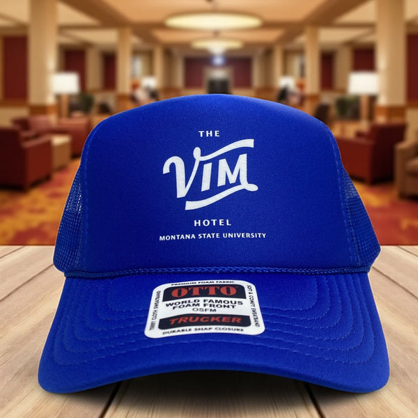 Blue Otto trucker hat with The VIM Hotel Montana State University logo printed in white on the front.